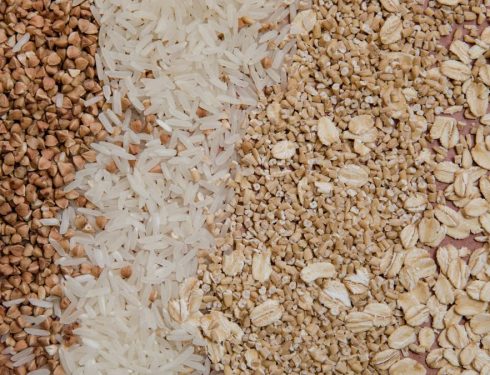 A variety of grains and cereals including oats, rice, and buckwheat arranged in a flat lay.