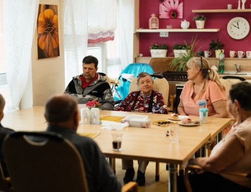 Seniors enjoying a meal in a nursing home dining room with caregivers in Karviná, Czechia.